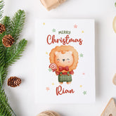 Christmas card with a lion holding a candy cane, surrounded by festive decorations on a white background.